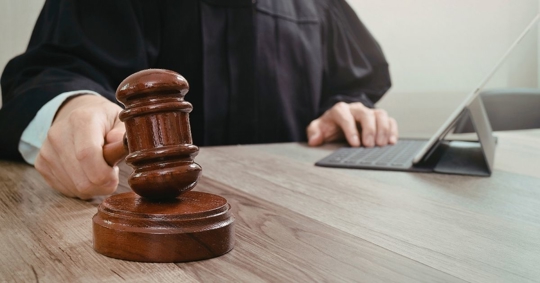 Judge holding gavel at desk with laptop