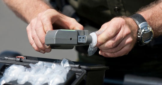 Law enforcement officer using a breathalyzer device for a sobriety test.