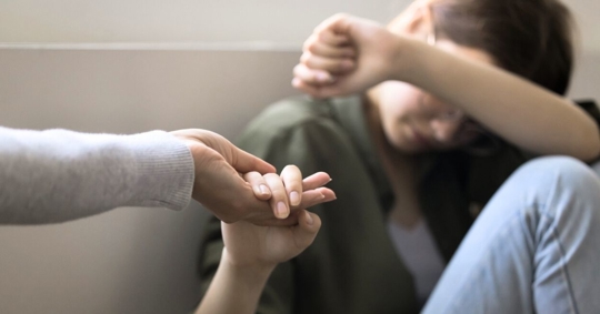 Troubled teenager taking hand of adult woman