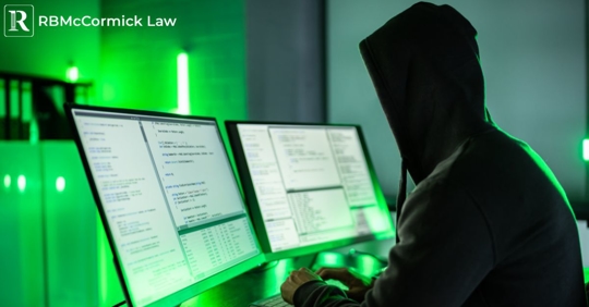 person in a hood looking at a computer screen